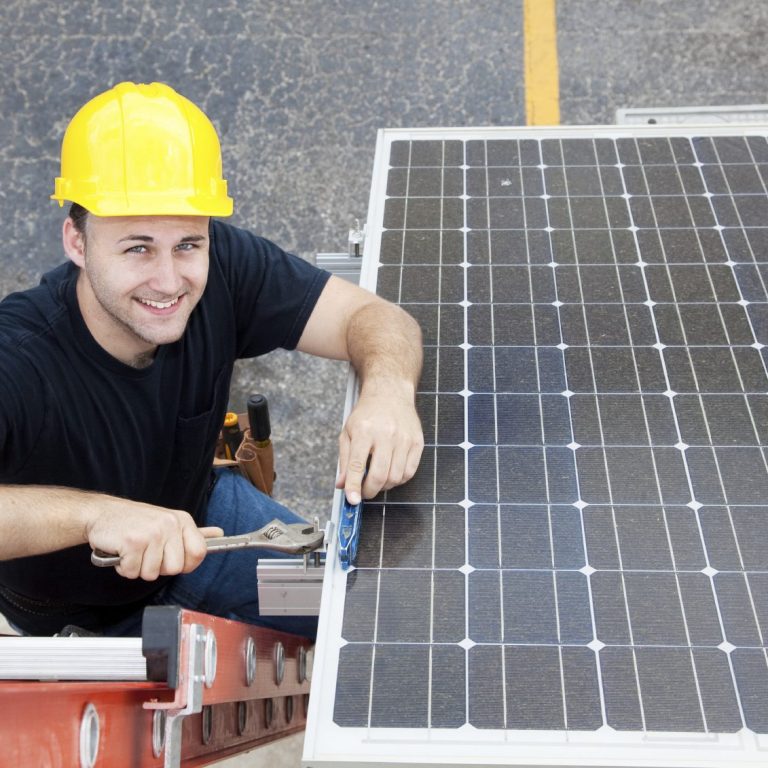 Mann mit gelbem Helm, der an Solarzellen auf einer Leiter arbeitet.