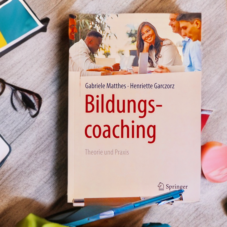 Buchcover "Bildungscoaching" mit Brille und Schulmaterialien im Hintergrund.